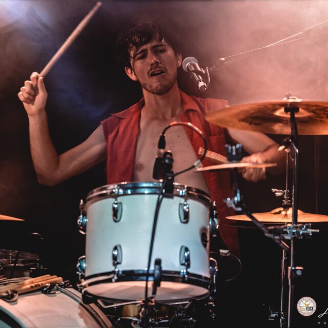 Raphaël Meyer joue de la batterie lors d'un concert de LAST RAINBOW à l'Altherax. Il est de face et à l'air de vouloir frapper une cymbale de manière extrêmement violente, signalez cet individu si vous le croisez