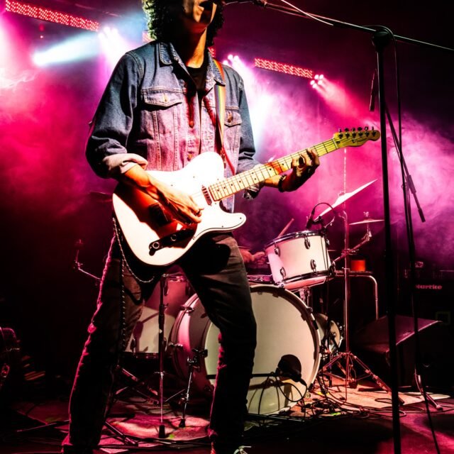 Alex Hutin chanteur de LAST RAINBOW jouant de la guitare électrique sur scène à l'Altherax